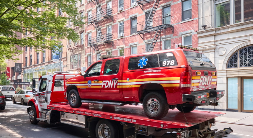 a new york city fire department vehicle sits on the bed of a tow truck
