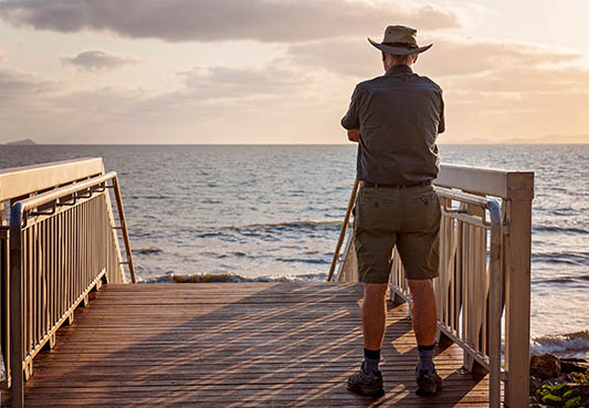 man standing atop steps looking out at the ocean