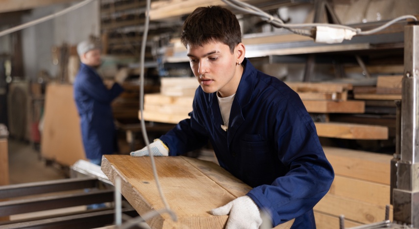 Young person working on a table saw in a commercial woodshop.