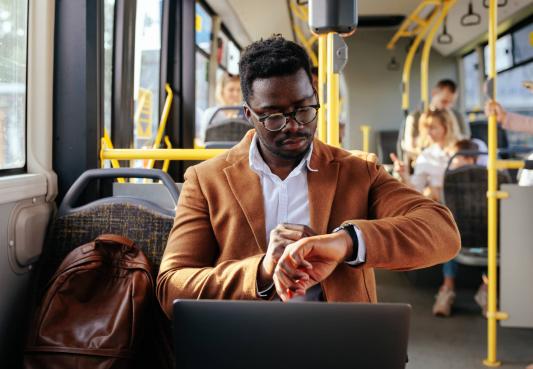man checks the time on his watch as he sits on the bus